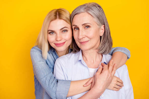 Photo portrait of daughter hugging her mum smiling wearing casual outfit isolated bright yellow color background - Valokuva, kuva