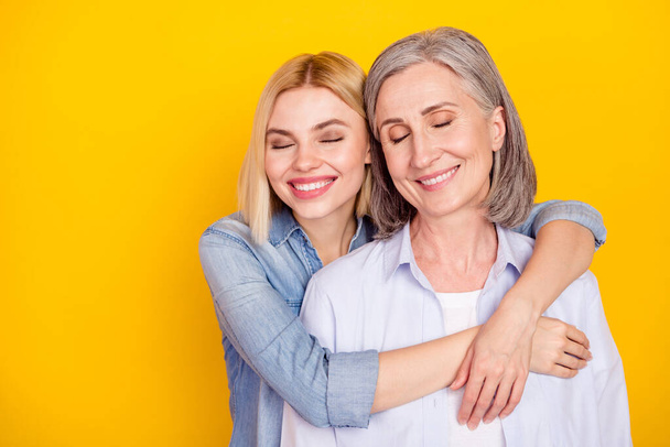Photo portrait of daughter embracing her mum smiling dreamy isolated bright yellow color background copyspace - Foto, afbeelding