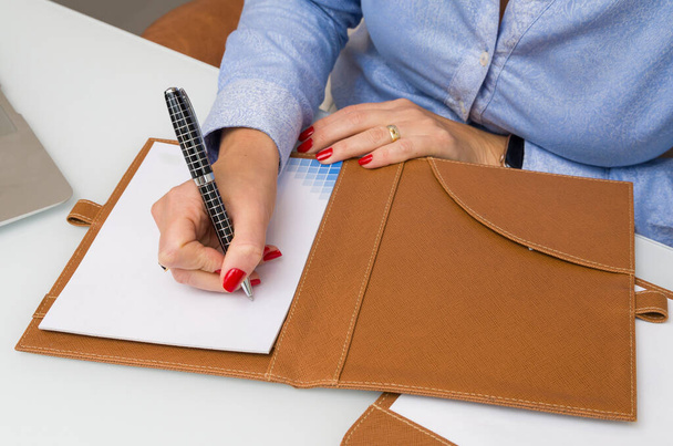 Nahaufnahme von Notizblock und Geschäftsfrau beim Schreiben - Foto, Bild