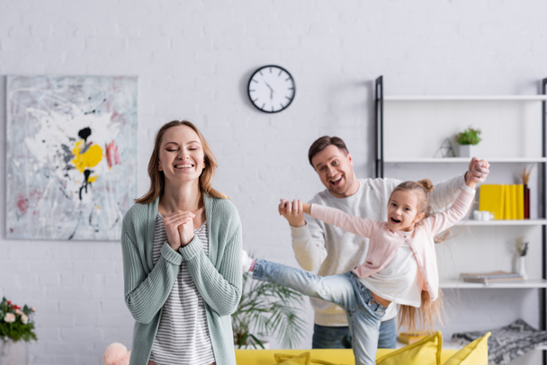 Cheerful woman standing near family having fun on blurred background  - Foto, immagini