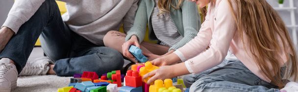 Cropped view of child and mother playing building blocks near father, banner  - Foto, imagen