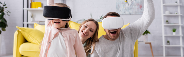 Cheerful father and daughter using vr headsets near mother at home, banner  - Foto, imagen