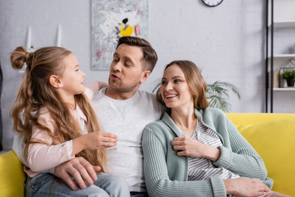 Child talking to smiling parents on couch  - Photo, image
