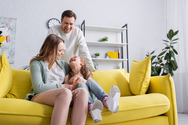 Smiling parents spending time with daughter at home  - Fotografie, Obrázek