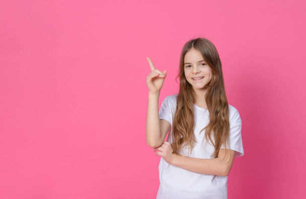 ragazza bianca 10 anni in un top bianco si presenta su uno sfondo rosa - Foto, immagini