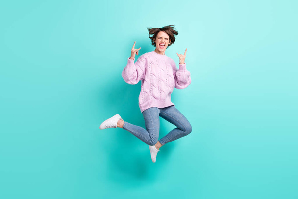 Full length photo of funky rude young woman wear violet sweater jumping showing hard rock sign isolated turquoise color background - Valokuva, kuva