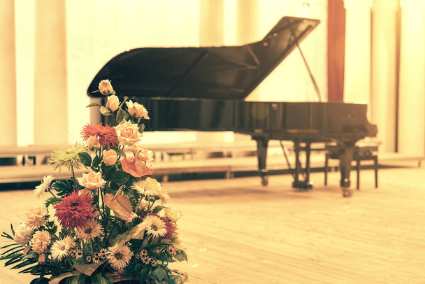 Рояль в Консерт-холле. Пианино стоит на пустой сцене. открыл черный рояль со стулом на деревянной концертной сцене. тонированные - Фото, изображение
