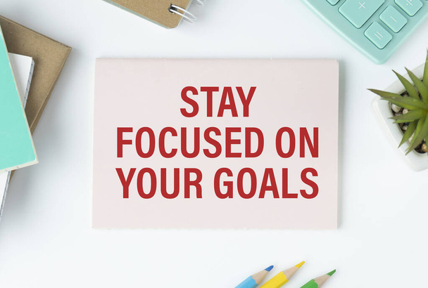 Inspirational quote - Stay focused on your goals. With text message on white paper book, pen, a cup of morning coffee, flower. - Foto, imagen