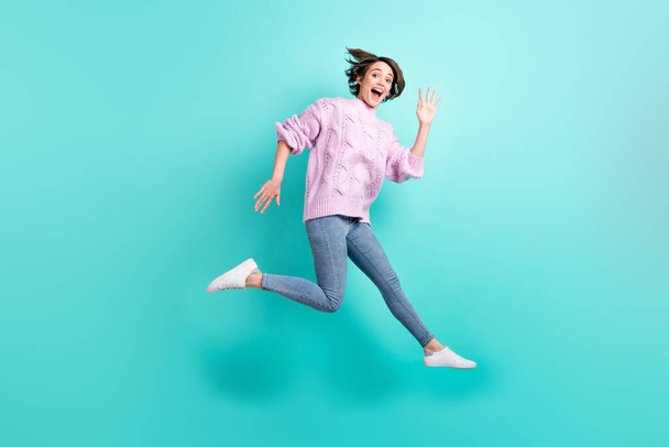 Full length photo of shiny excited young lady dressed purple pullover jumping waving arm isolated teal color background - Foto, Imagen