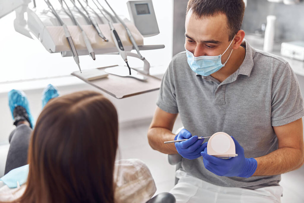 Vidám pozitív fogorvos és kliens a fogászatban. Egymásra néznek és mosolyognak. Női ügyfél ül a székben - Fotó, kép