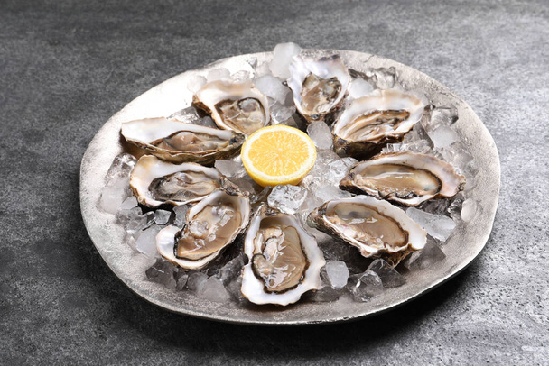 Delicious fresh oysters with lemon on grey table - Foto, Imagem