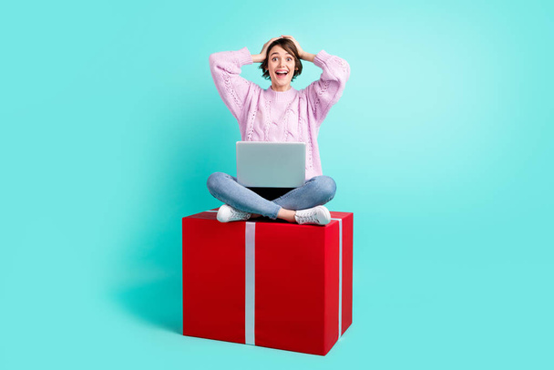 Photo of lucky excited lady dressed purple pullover sitting present holding modern device arms head isolated teal color background - Foto, immagini