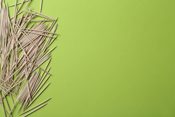 Wooden toothpicks on green background, flat lay. Space for text - Foto, Bild