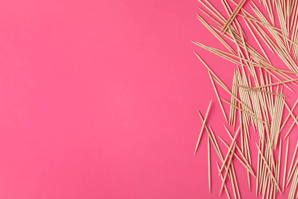 Деревянные зубочистки на розовом фоне, плоский уголок. Пространство для текста - Фото, изображение