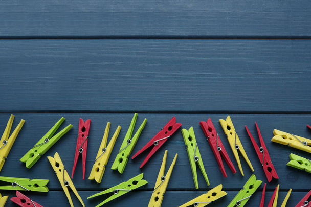 Colorful plastic clothespins on blue wooden background, flat lay. Space for text - Фото, зображення
