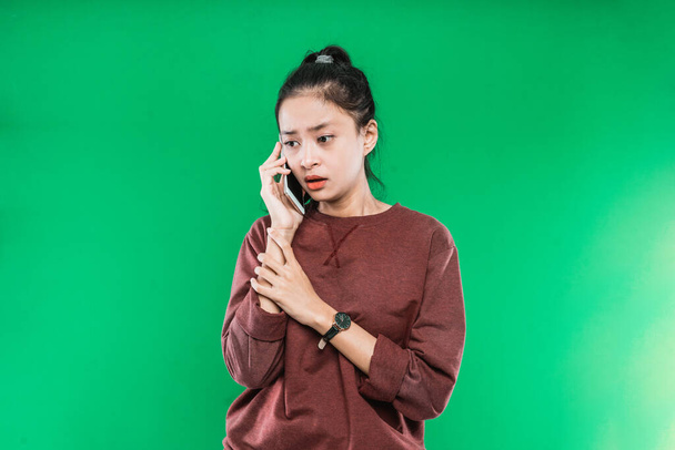 Portrét mladé asijské ženy hovořící do telefonu se smutným, šokovaným výrazem - Fotografie, Obrázek