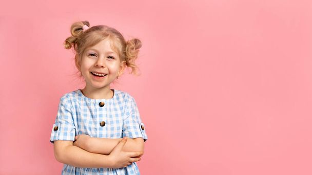 egy szőke kislány rózsaszín, elszigetelt háttérrel, aranyos mosollyal. banner szöveges szöveggel. - Fotó, kép