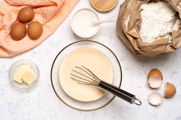 Işık masasında malzemelerle krep yapmak için hamur yapma işlemi yumurta ve un karıştırıcı ile karıştırılır.. - Fotoğraf, Görsel