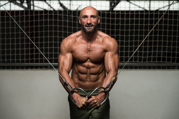 Muscular Bodybuilder Performing Cable Crossover - 写真・画像