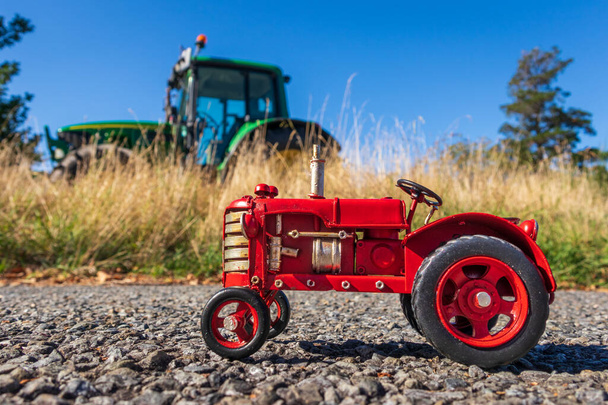 One small model tin model tractor, with a big green tractor in the background. - Photo, image