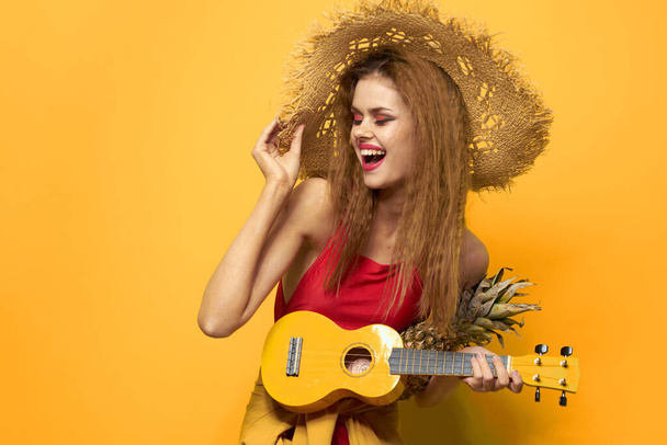 Vrouw met Ukulele stro hoed levensstijl Exotische gele achtergrond - Foto, afbeelding