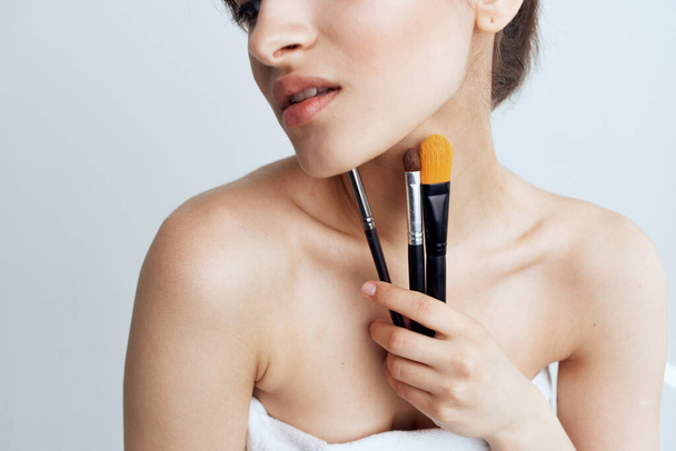 Jolie femme épaules nues cosmétiques pinceaux de maquillage soins - Photo, image