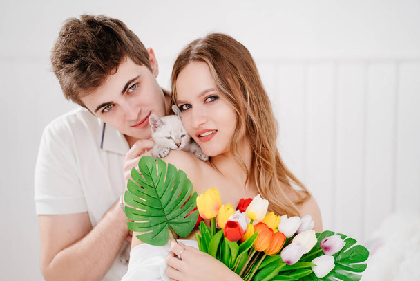 a man gave his beloved woman a bouquet of colorful tulips and a white kitten. - Fotografie, Obrázek