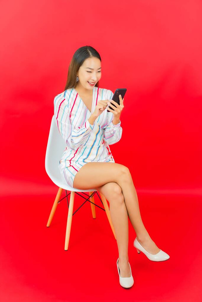 Portret mooie jonge aziatische vrouw met slimme mobiele telefoon op roze kleur achtergrond - Foto, afbeelding