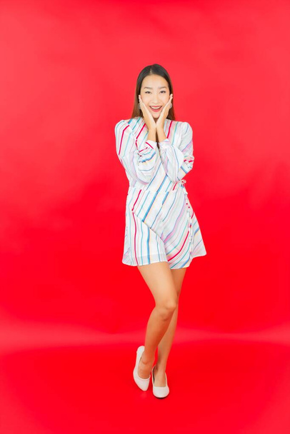 Portrait belle jeune femme asiatique sourire avec beaucoup d'action sur fond rouge - Photo, image