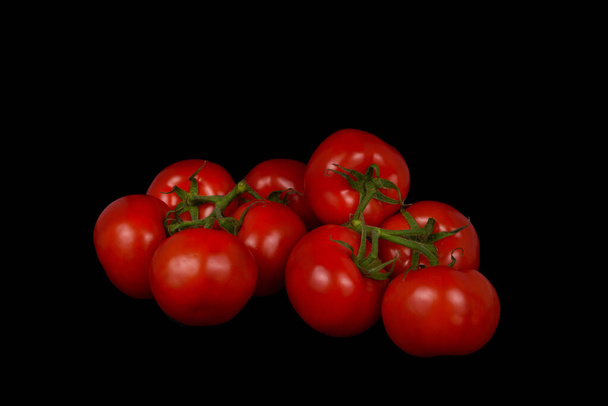 Nine ripe tomatoes on branches on a black background. - Foto, Imagen