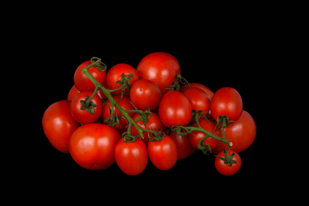 Large branch of tomatoes on a black background - Φωτογραφία, εικόνα