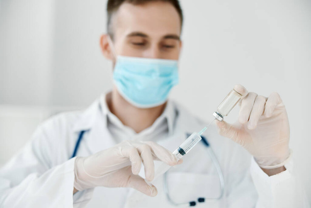 doctor in a medical mask holds a syringe in his hand vaccine chemical liquid covid vaccination - Φωτογραφία, εικόνα