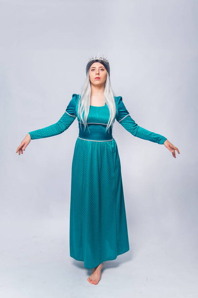 Full length portrait of a princess in a medieval, fantasy, turquoise dress with ash hair and a silver crown, posing isolated on a white background. - Fotoğraf, Görsel