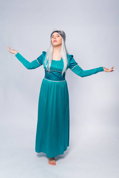 Full length portrait of a princess in a medieval, fantasy, turquoise dress with ash hair and a silver crown, posing isolated on a white background. - Foto, Imagen