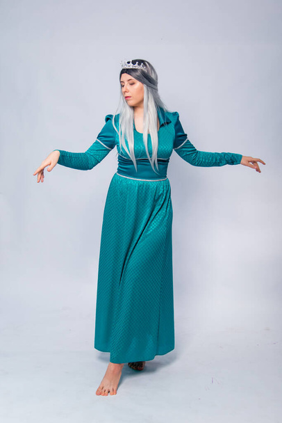 Full length portrait of a princess in a medieval, fantasy, turquoise dress with ash hair and a silver crown, posing isolated on a white background. - Φωτογραφία, εικόνα
