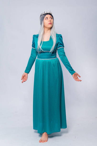 Full length portrait of a princess in a medieval, fantasy, turquoise dress with ash hair and a silver crown, posing isolated on a white background. - 写真・画像