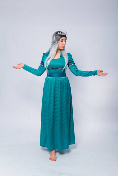 Full length portrait of a princess in a medieval, fantasy, turquoise dress with ash hair and a silver crown, posing isolated on a white background. - Foto, immagini
