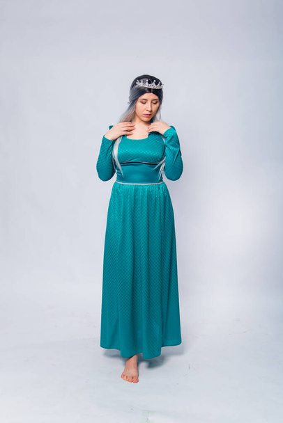 Full length portrait of a princess in a medieval, fantasy, turquoise dress with ash hair and a silver crown, posing isolated on a white background. - Foto, Bild