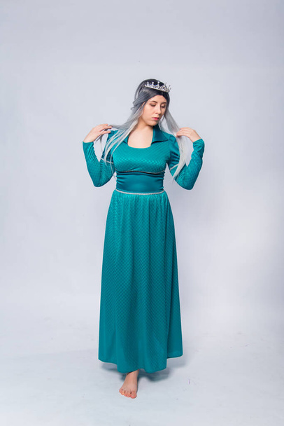 Full length portrait of a princess in a medieval, fantasy, turquoise dress with ash hair and a silver crown, posing isolated on a white background. - Foto, Imagen