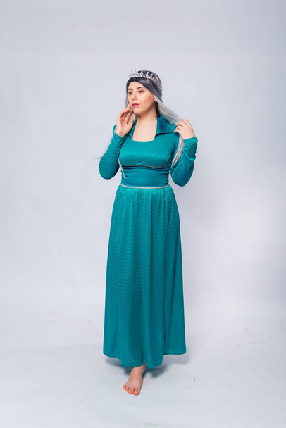 Full length portrait of a princess in a medieval, fantasy, turquoise dress with ash hair and a silver crown, posing isolated on a white background. - Foto, afbeelding