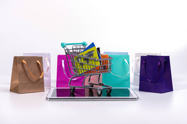 tablet, mini shopping cart with credit cards and colourful paper bags isolated on white - Valokuva, kuva