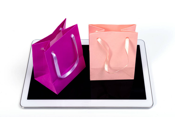 small colorful shopping bags on modern tablet against white background, online shopping concept - Foto, afbeelding