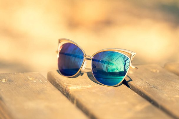 Fashion kattenoog zonnebril model voor dames met blauwe lenzen en gouden frame shoot buiten in een zonnige dag close-up. Selectieve focus  - Foto, afbeelding