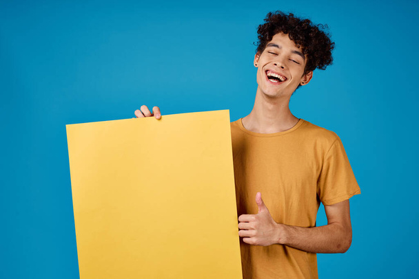 Typ mit lockigem Haar aus gelben Astern in seinen Händen Studio blauer Hintergrund - Foto, Bild