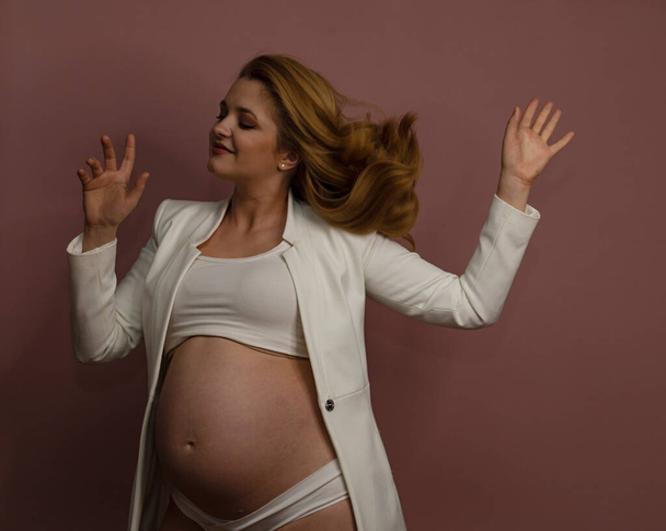 portrait of a beautiful pregnant woman on a pink background - Photo, Image
