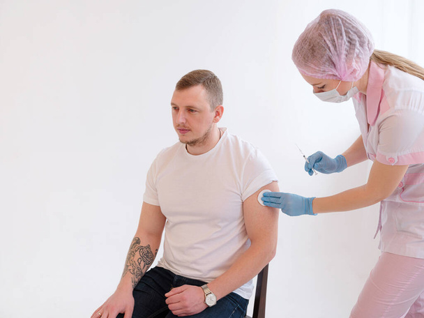 男性の患者の肩のcovid 19ワクチン注射用量を作る注射器を保持している女性医師.インフルエンザワクチン臨床試験の概念コロナウイルス治療副作用 - 写真・画像