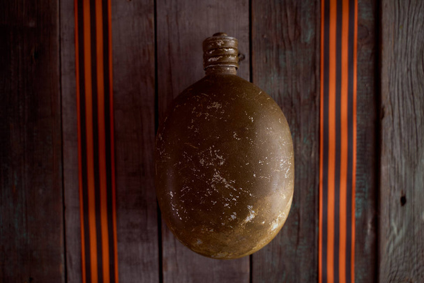 O frasco do soldado fica entre as fitas de São Jorge em uma mesa de madeira. Foto de alta qualidade - Foto, Imagem