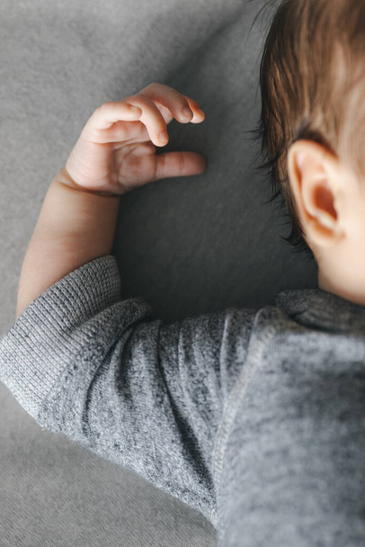 Foto recortada de bebê recém-nascido caucasiano dormindo em fundo cinza para artigos sobre doenças do ouvido da infância - Foto, Imagem