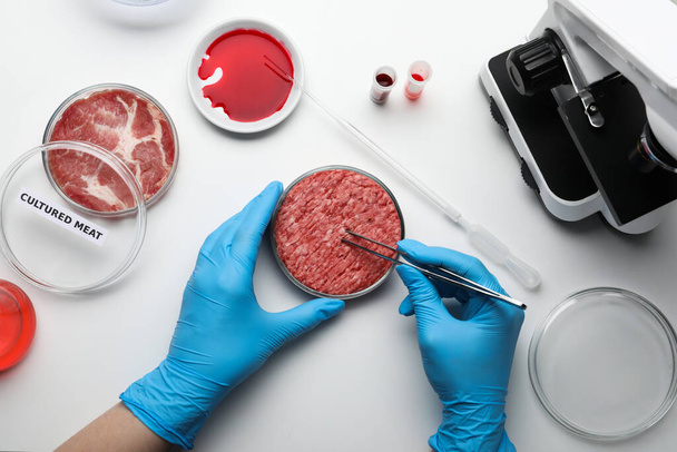 Scientist taking sample of minced cultured meat at white lab table, top view - Foto, Bild