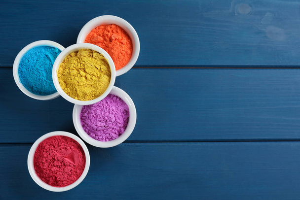 Colorful powder dyes on blue wooden background, flat lay with space for text. Holi festival - 写真・画像